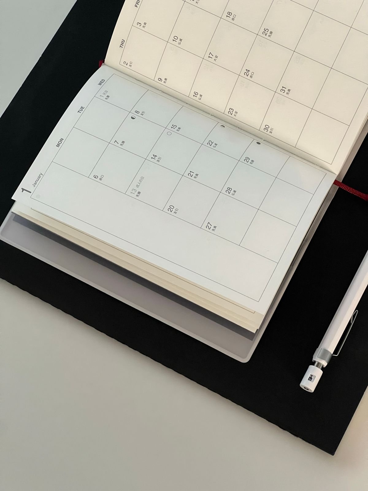 Open calendar with a pen and notebook on a desk.